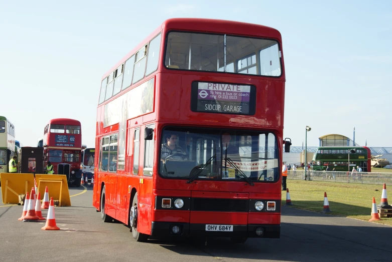 a double decker bus driving through an orange cone