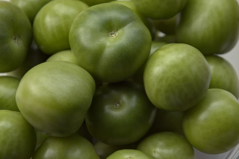 large group of green apples placed in a white bowl