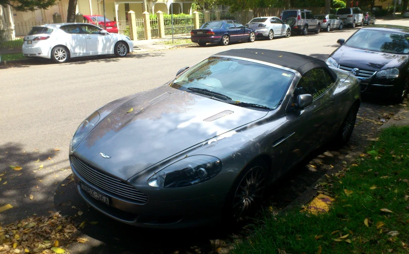 a silver car on a sidewalk with cars parked