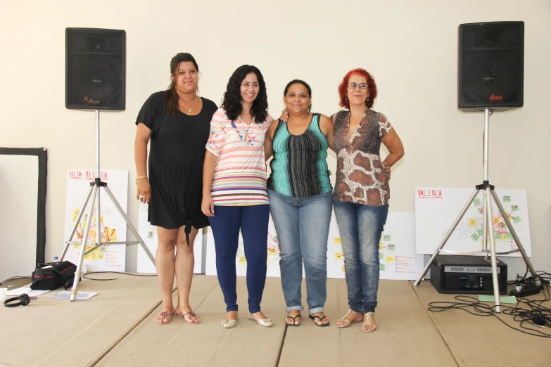 some women standing in front of several speakers