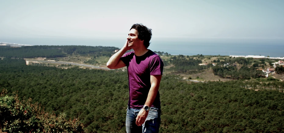 a man on top of a mountain talks on his phone