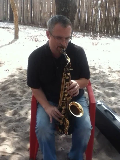 a man plays a saxophone while sitting in a chair