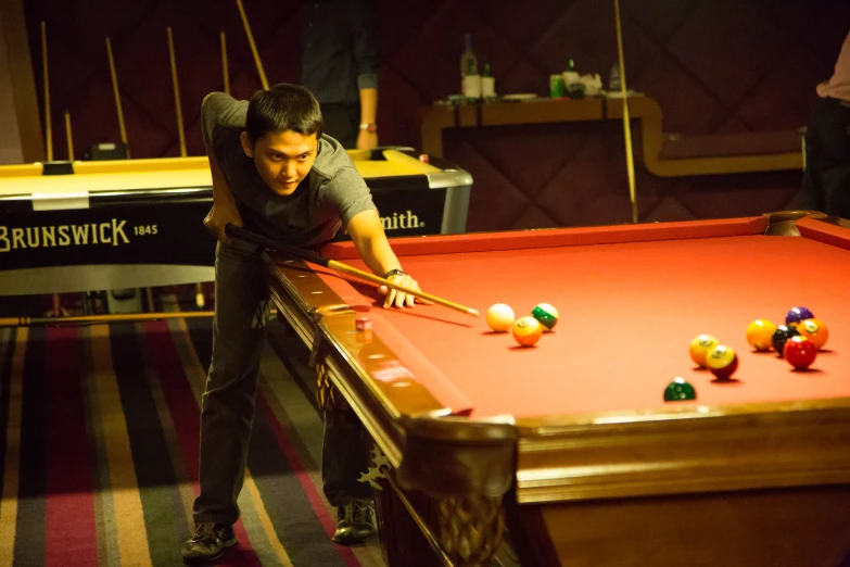 a man leans forward to hit the ball at a pool table