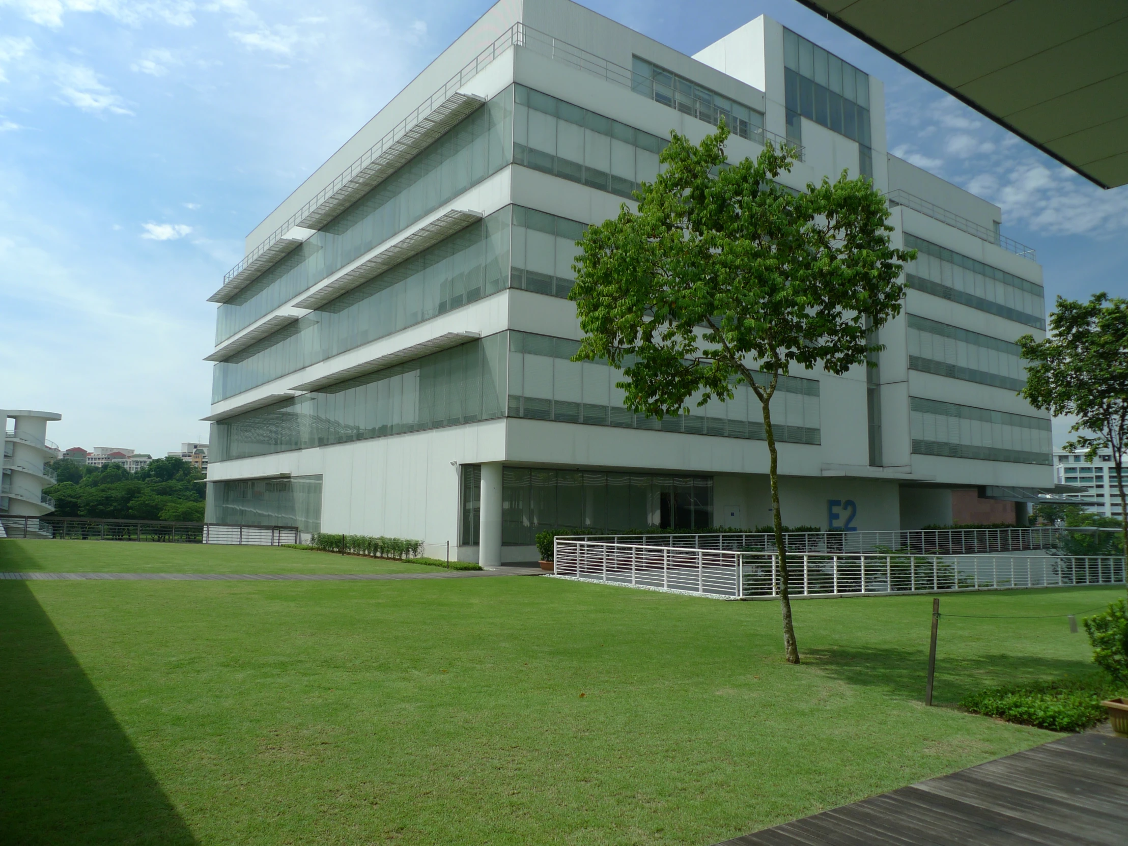 a building that has a grass field with trees in front of it