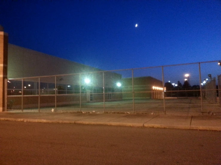 a fenced in area with lights on it at night