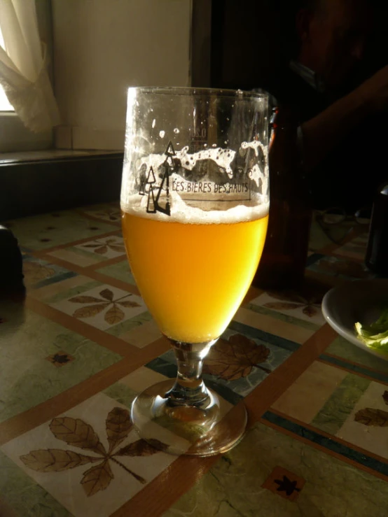 a wine glass filled with a beer on top of a table