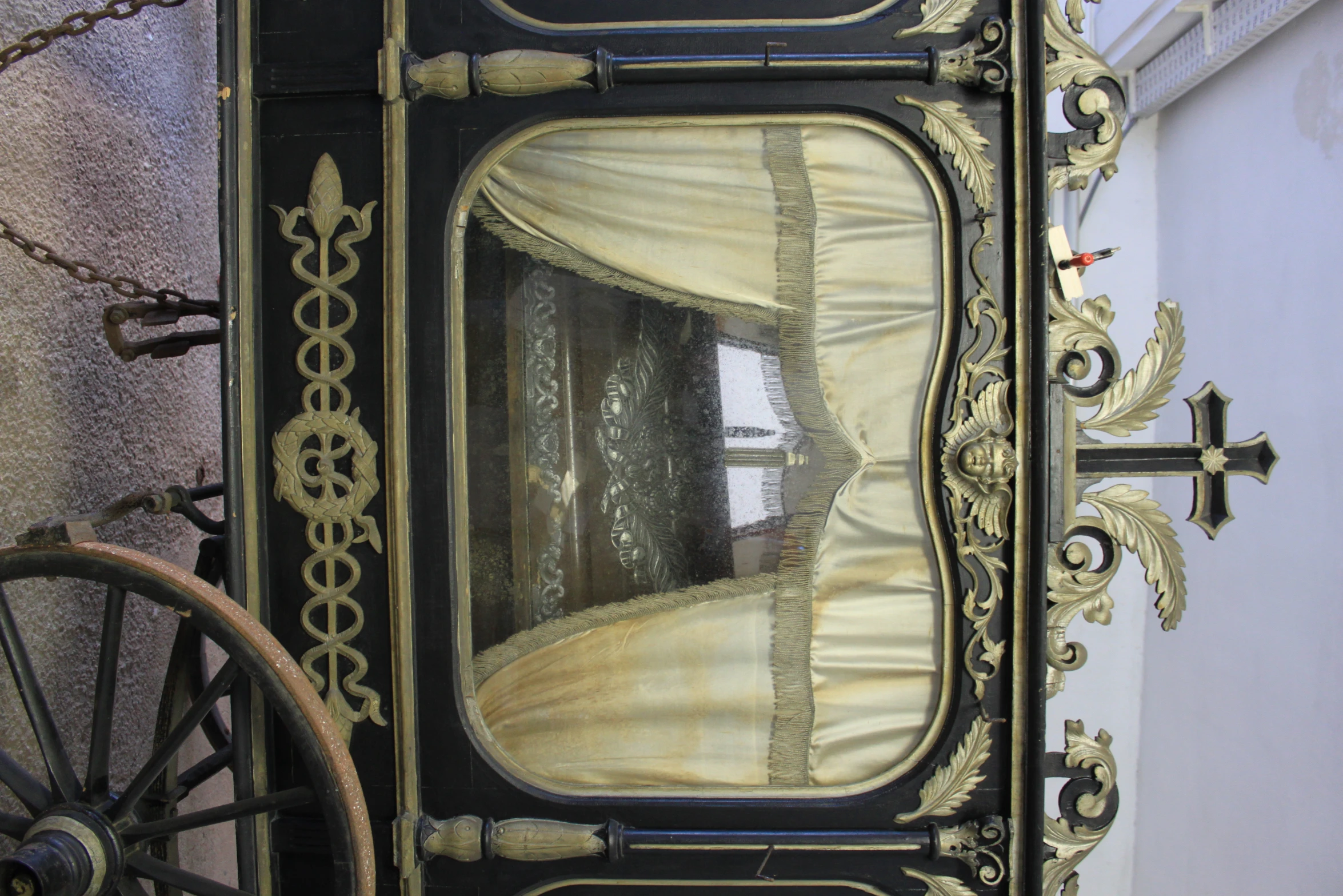 a fancy black and gold painted wagon with curtains on top