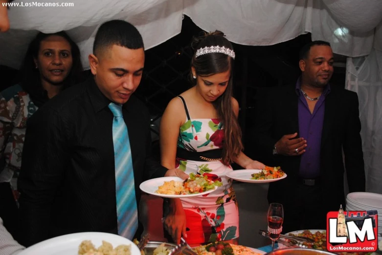 two people looking at plates of food at a party