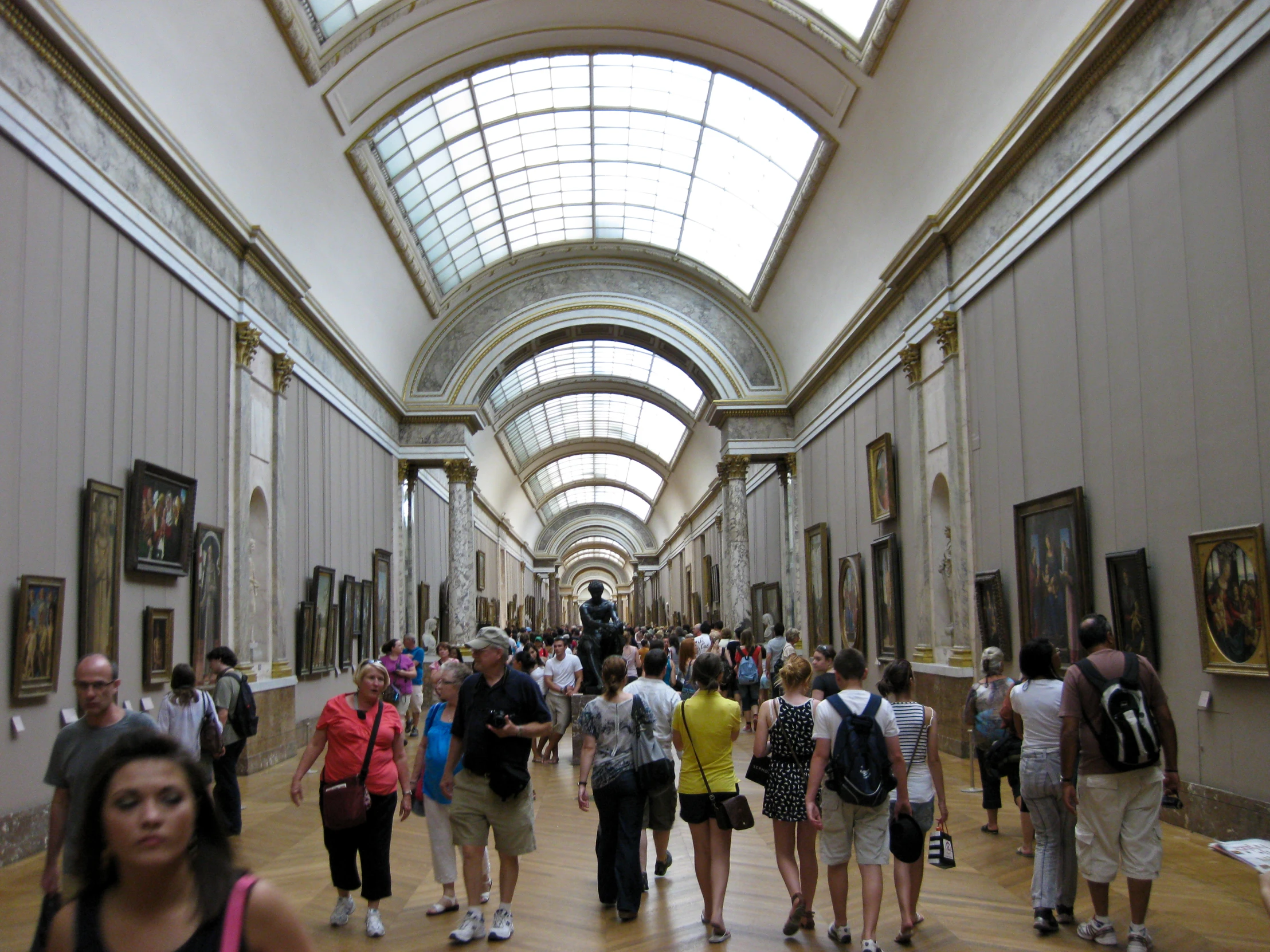 a large group of people walk inside of an art museum