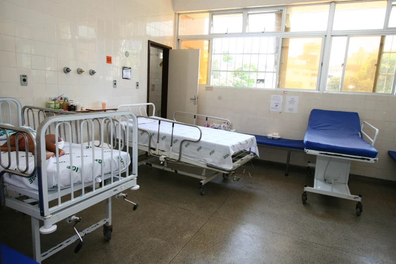 three hospital beds with white plastic covers and blue covers