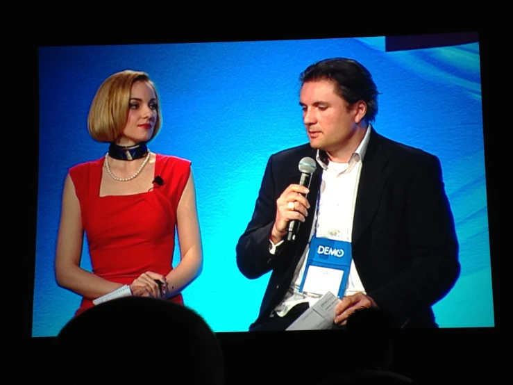 a man and woman are sitting in front of a large screen