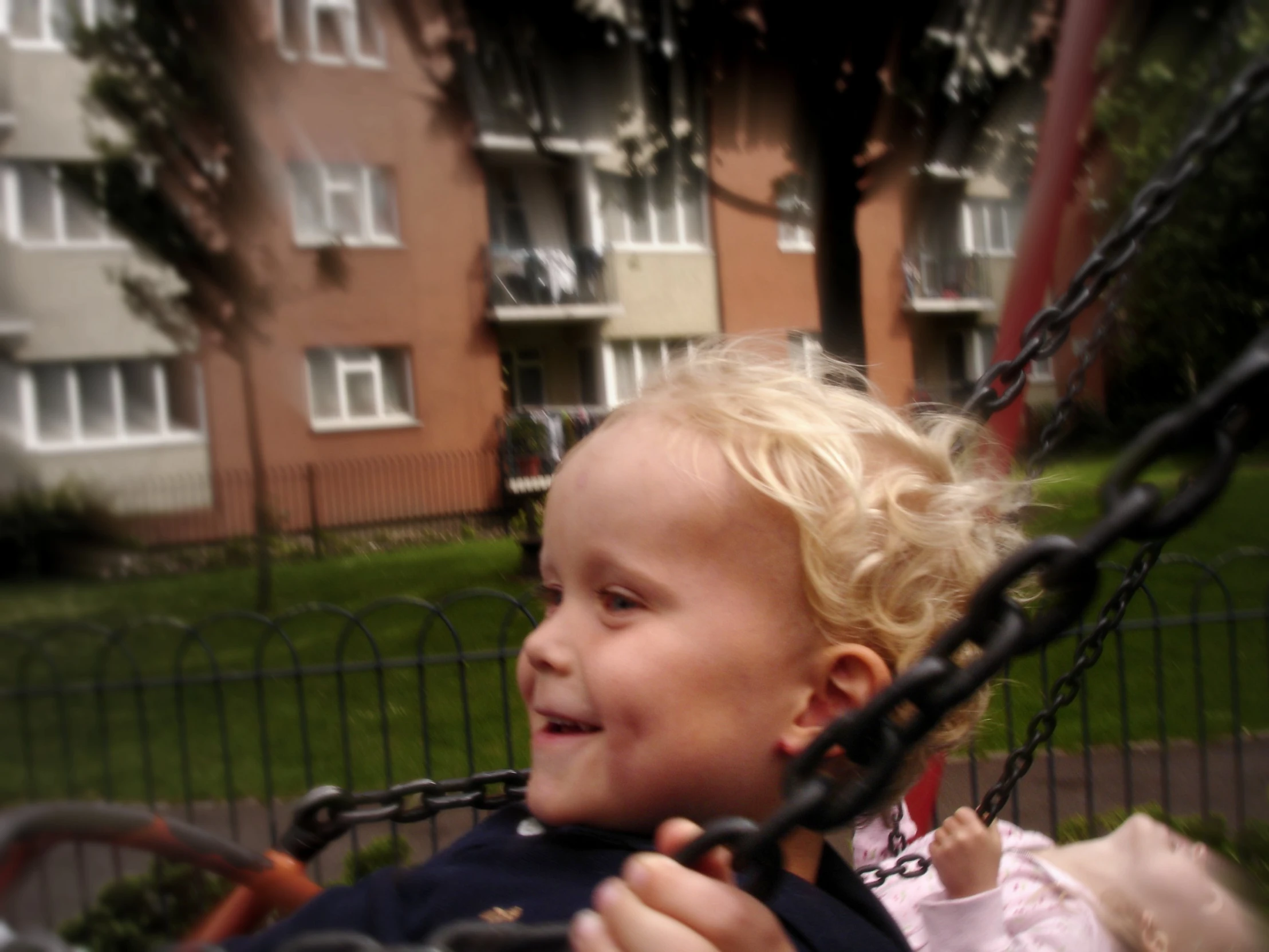 a little girl riding on a swing set in the park