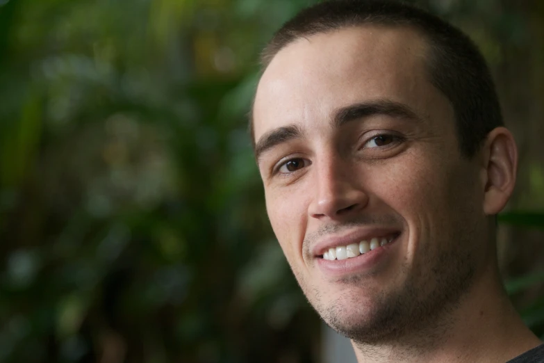 an attractive young man smiles and looks to the side