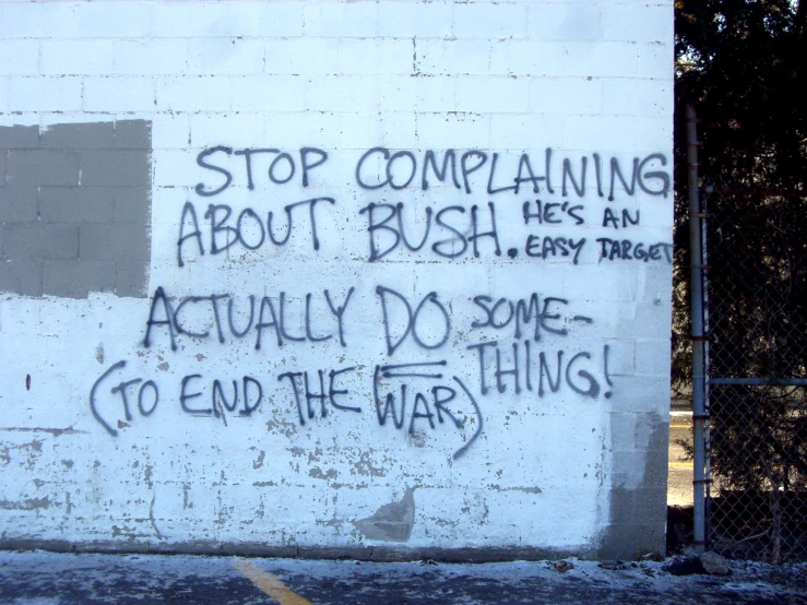graffiti written on a white brick wall saying stop comparing about bush he's an actual do