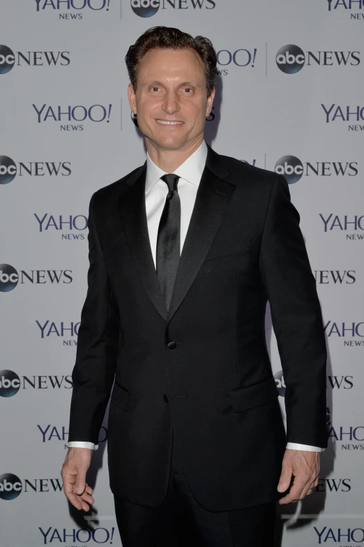 a man is in black tuxedo and standing by the yahoo news logo
