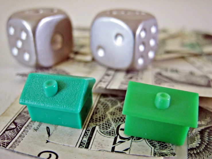 a pair of green and white cubes sit on top of two dollar bills