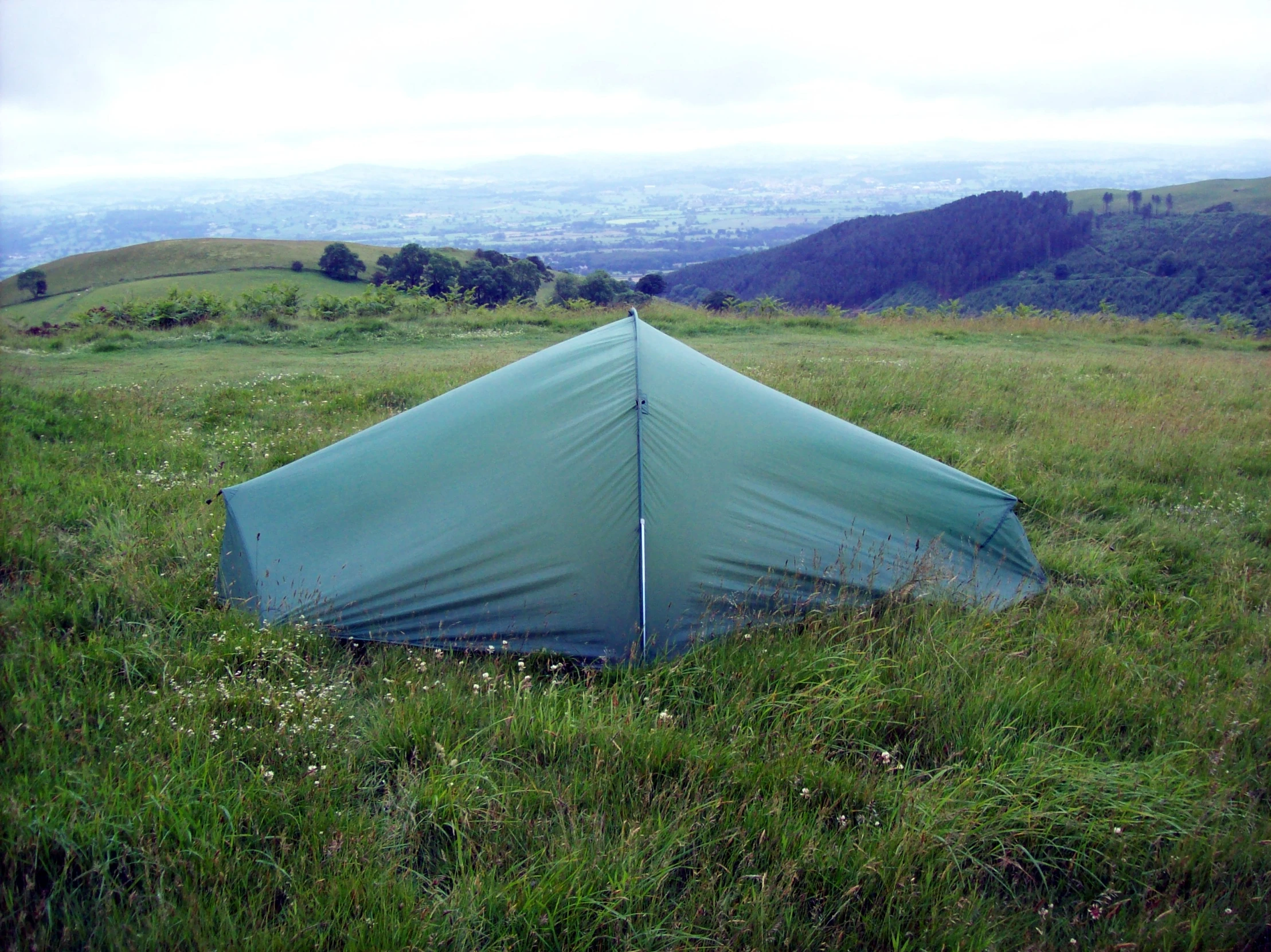 a tent sitting on top of a lush green hillside