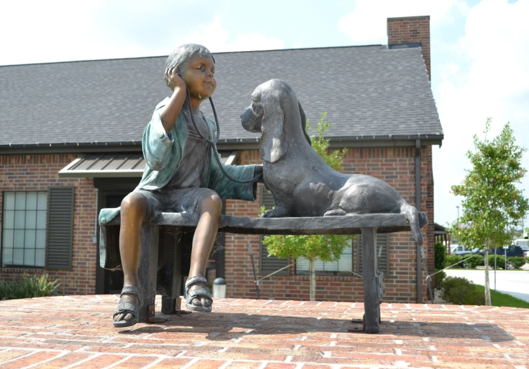 a statue of a child and a dog on a bench