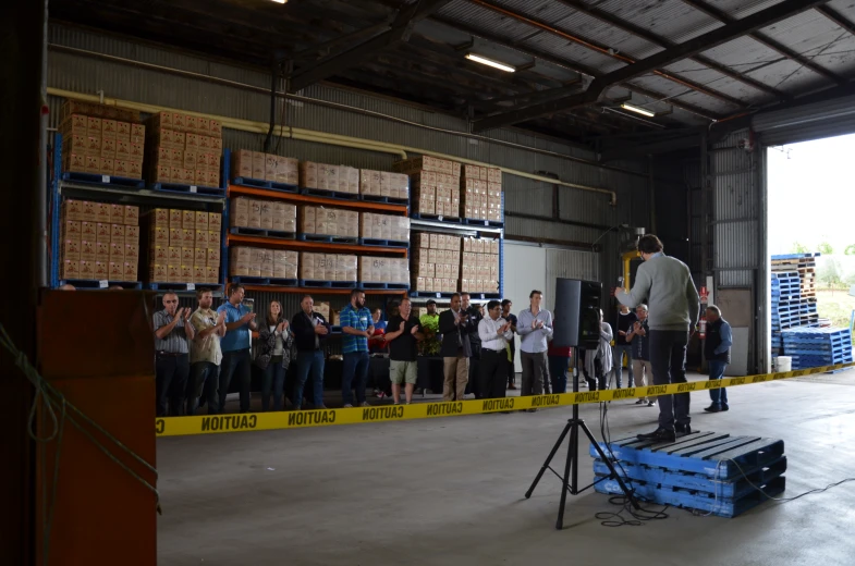 a man speaking to a crowd at a warehouse