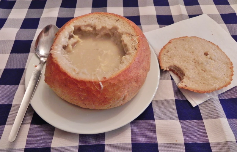 soup in a bowl inside of a bread bowl on a plate
