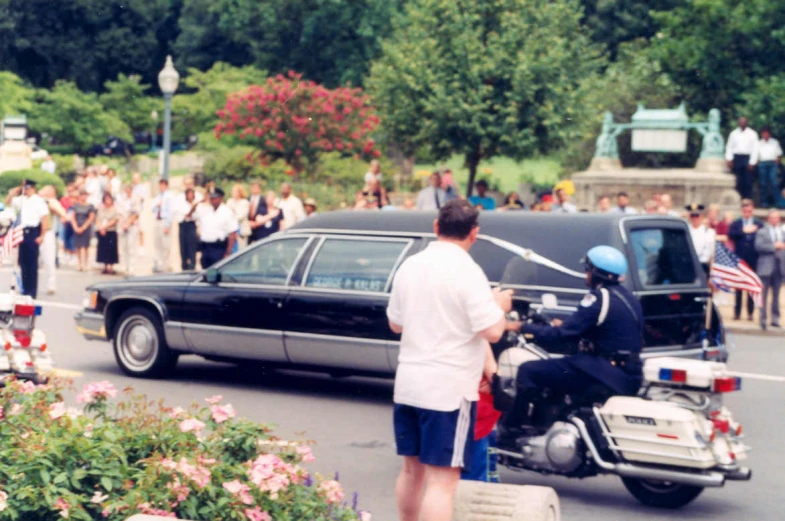 a crowd watches as people stand in front of a car