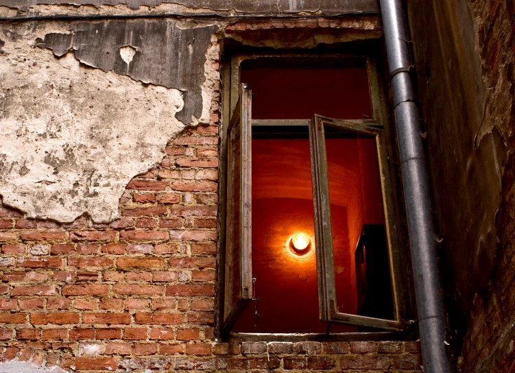 a window with a lamp beside it and peeling brick walls