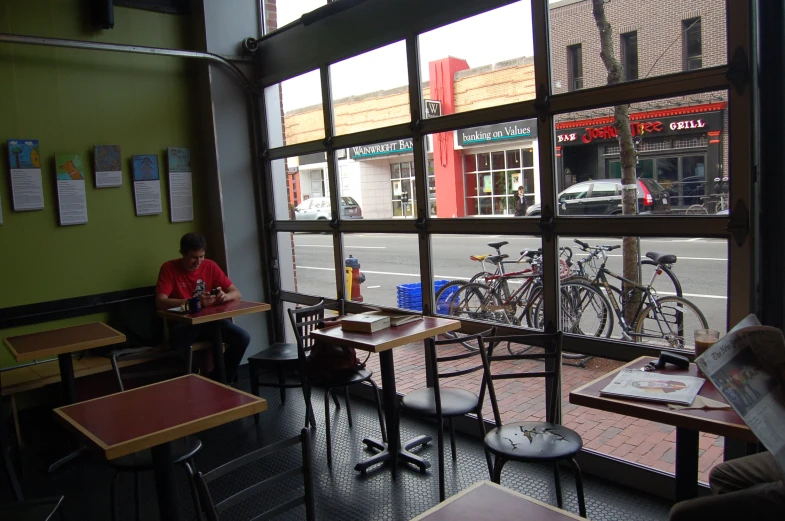 two people sitting at tables by bikes and looking outside