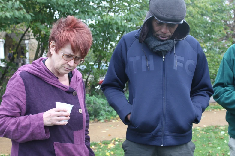 a man holding a drink standing next to two women