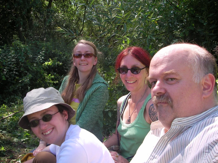 four people sitting outside, with trees in the background