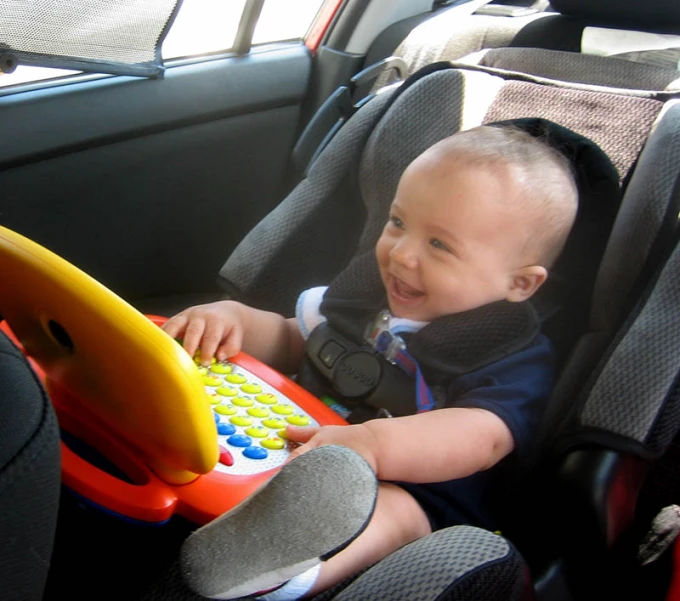 a baby boy sitting in a car seat and smiling