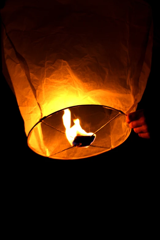 a hand holding the inside of a paper lantern in the dark