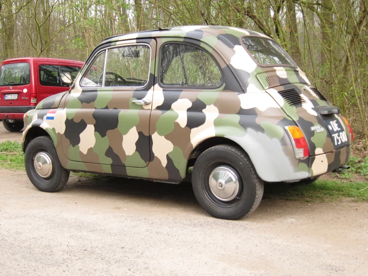 a camouflage car is parked by a red van