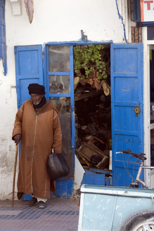 an old man walks into a building with a small door