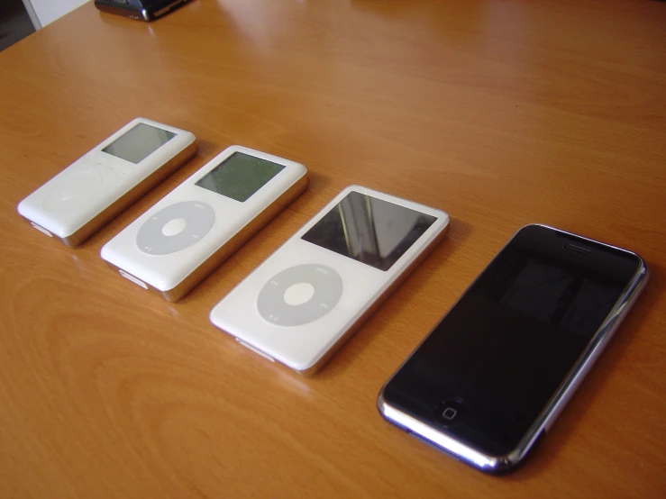 three ipods sitting next to a smart phone