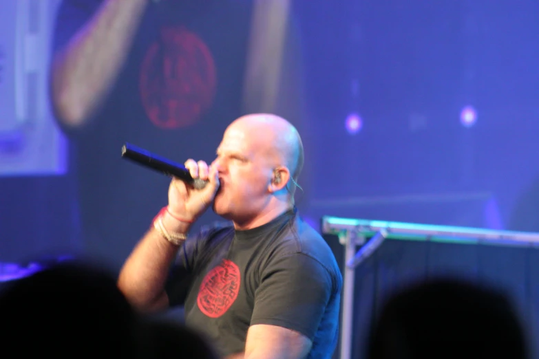 a bald man in black shirt with a microphone in his hand