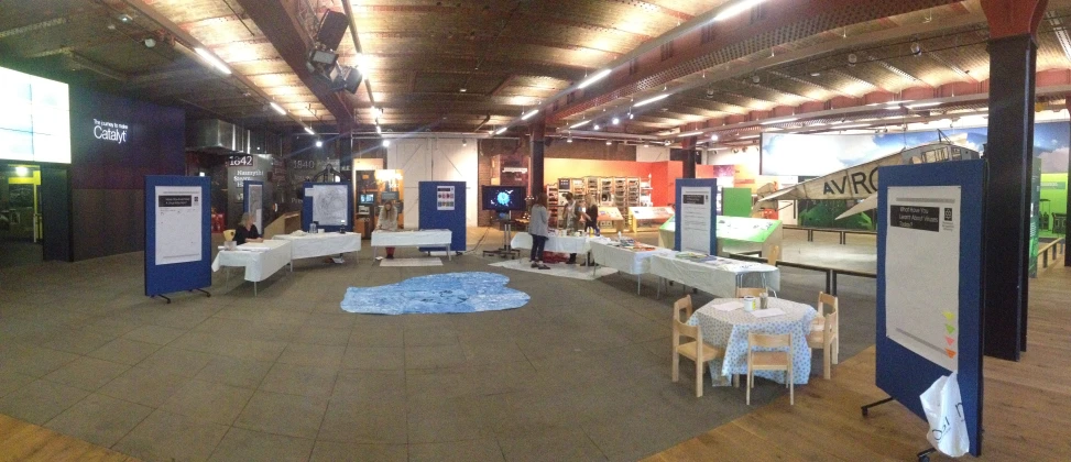 a large room with white tables and chairs and blue flags