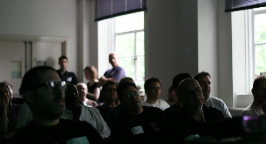 the men sit behind each other watching a screen