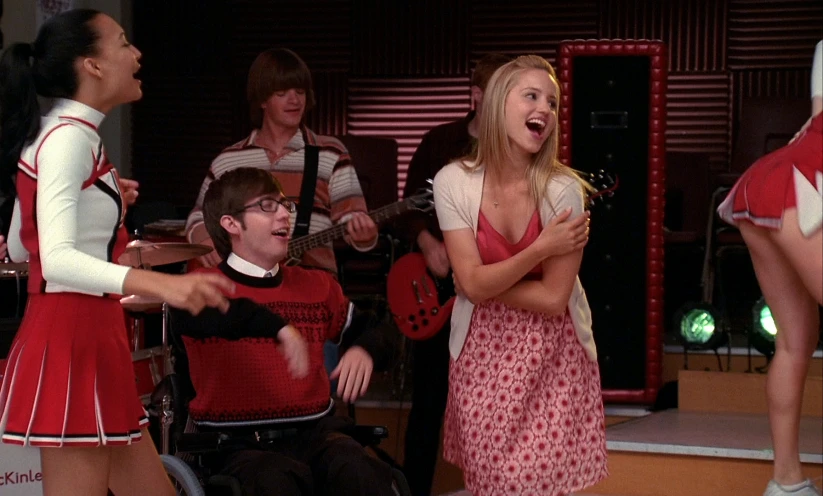 a young woman singing while two men play the guitar and some girls in wheelchairs