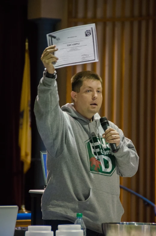 a man holding up a microphone and standing behind a microphone