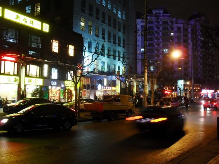 a crowded street at night with neon lights and cars driving down it