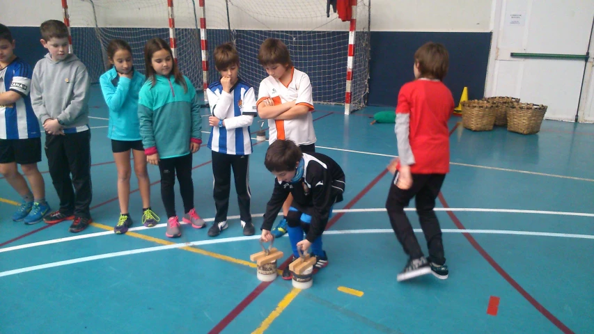 some young children are standing on a court with a soccer ball