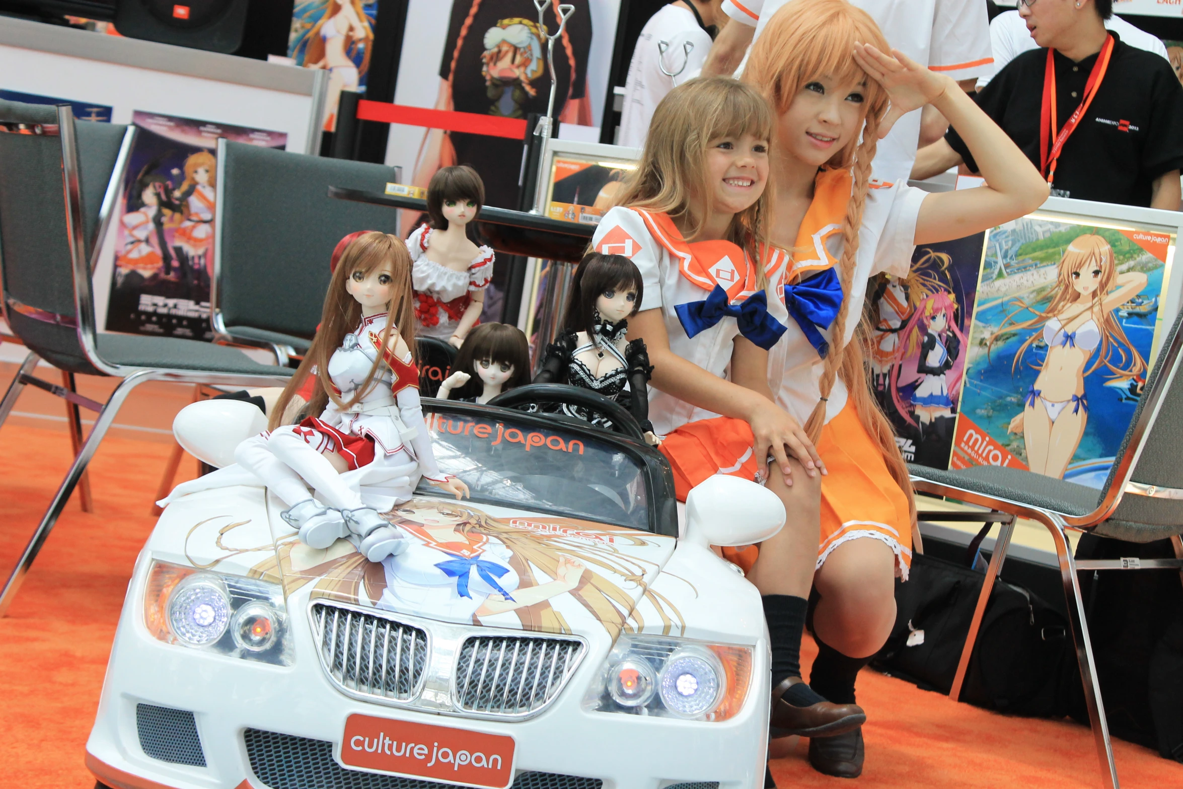 two beautiful young ladies sit on top of a toy car