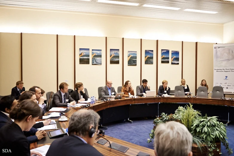 group of businesspeople at conference table listening to speakers