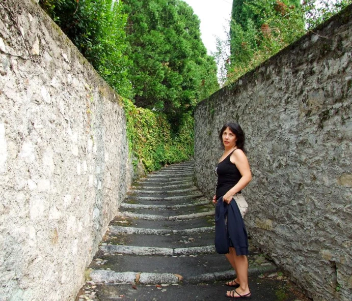 a woman wearing sandals stands at the bottom of a steep set of stone stairs