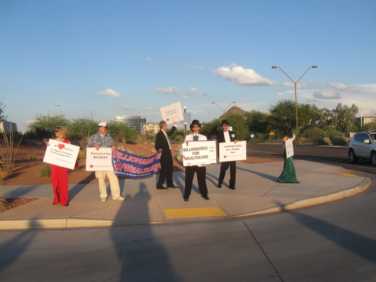 four people standing on the road holding signs