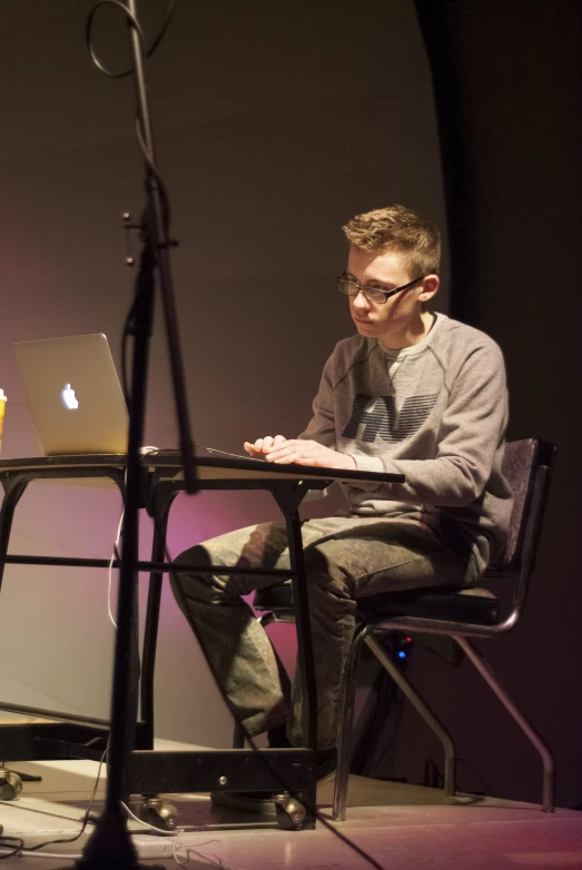 a man is sitting at a table in front of a laptop