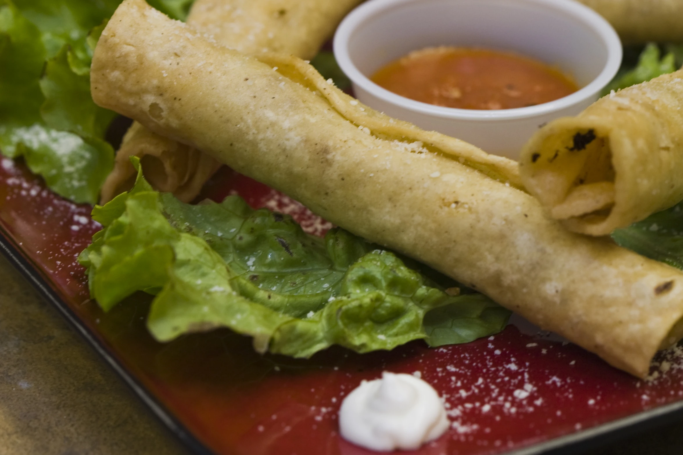 an egg roll is sitting on top of lettuce and sauce