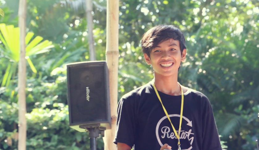  standing outside with trees and plants behind him