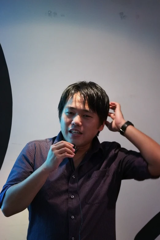 a young man holds his hair comb up to his ears