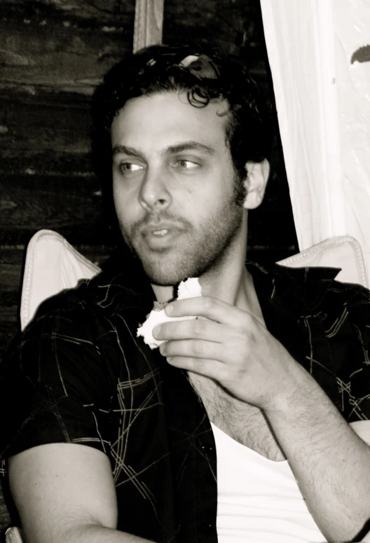 man sitting and eating cake in black and white po